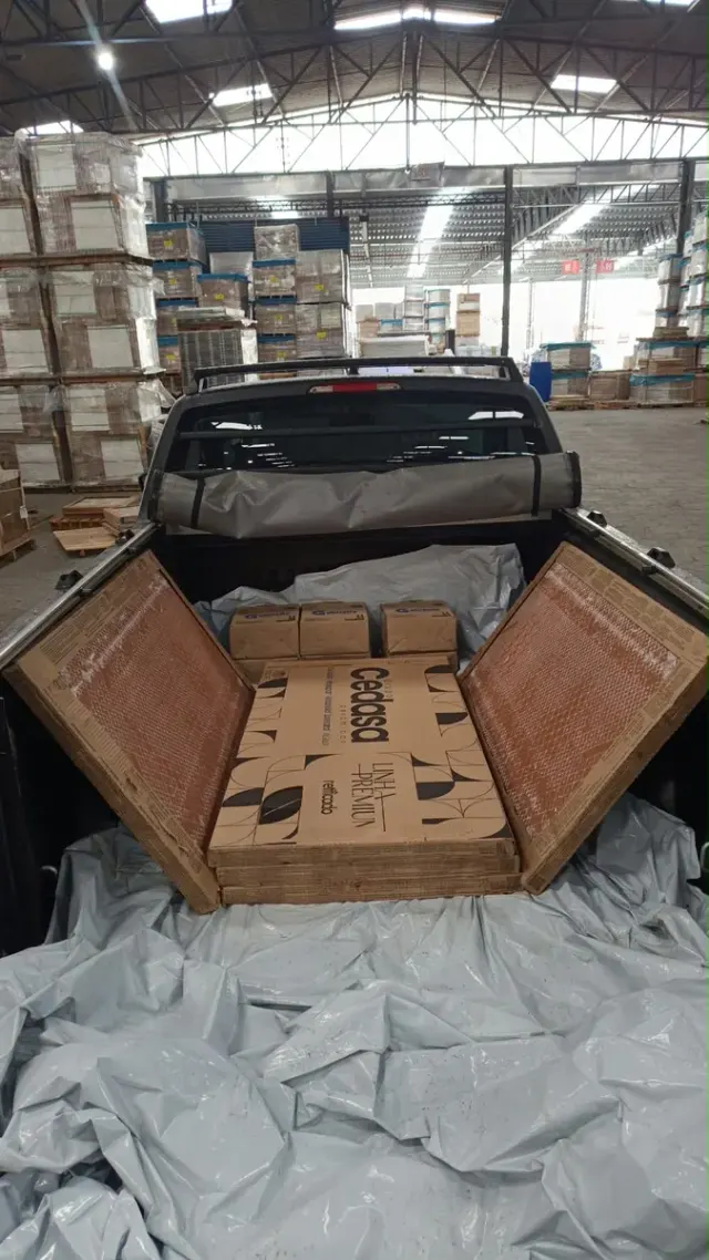 Caixas de porcelanato protegidas com lona na caçamba do utilitário